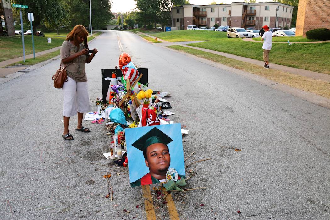 A women stands in front of flowers and placards in Ferguson, MO, Monday, August 25, 2014, in what constitutes one of the three installations in memorial of Michael Brown, killed earlier this month. This memorial is located in the middle of Canfield drive, on the spot he has been shot at by officer Darren Wilson, promoting days of unrest in the St Louis suburb. (Yann Schreiber)