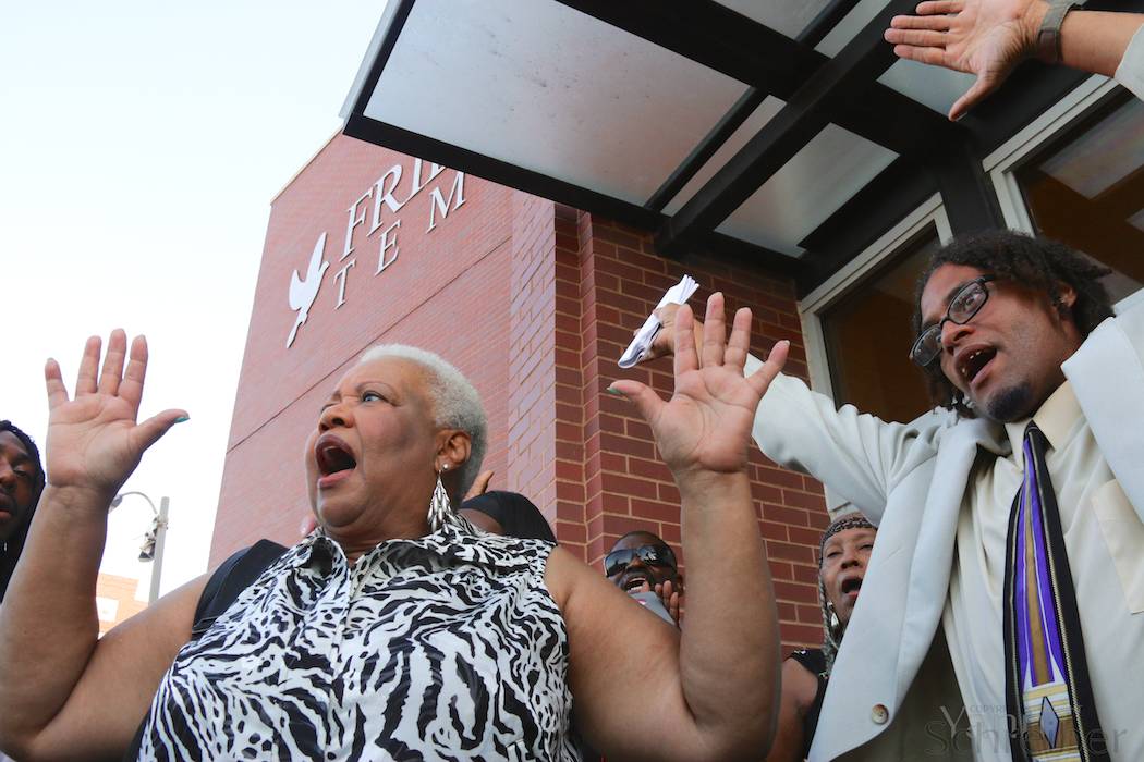 A waiting crowd sings "We Shall Overcome" while raising their hands in reference to the "Hands Up Don’t Shoot" slogan during the funeral service for Michael Brown in St Louis, MO, Monday, August 25, 2014. The service, held in the Friendly Temple Missionary Baptist Church, attracted thousands, including civil rights figures Al Sharpton and Jesse Jackson. (Yann Schreiber)