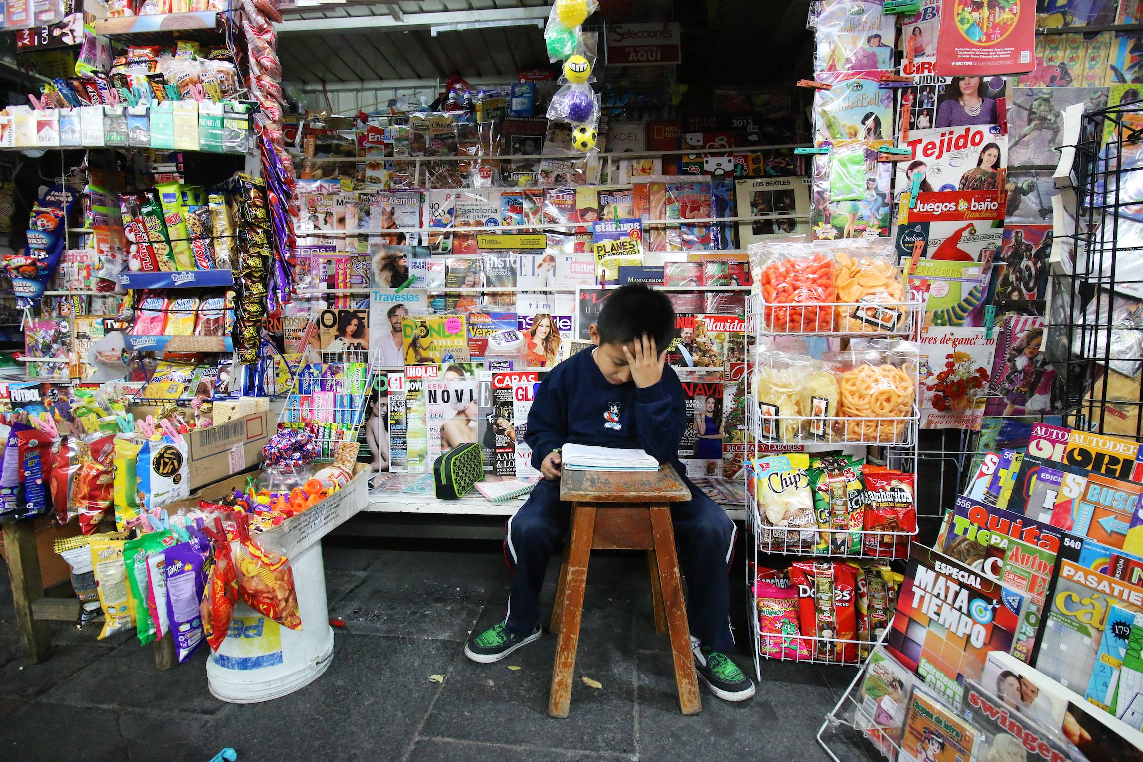 A boy studies, sitting in a kiosk in the streets of Mexico City, D.F., Friday, Nov. 21, 2014.
