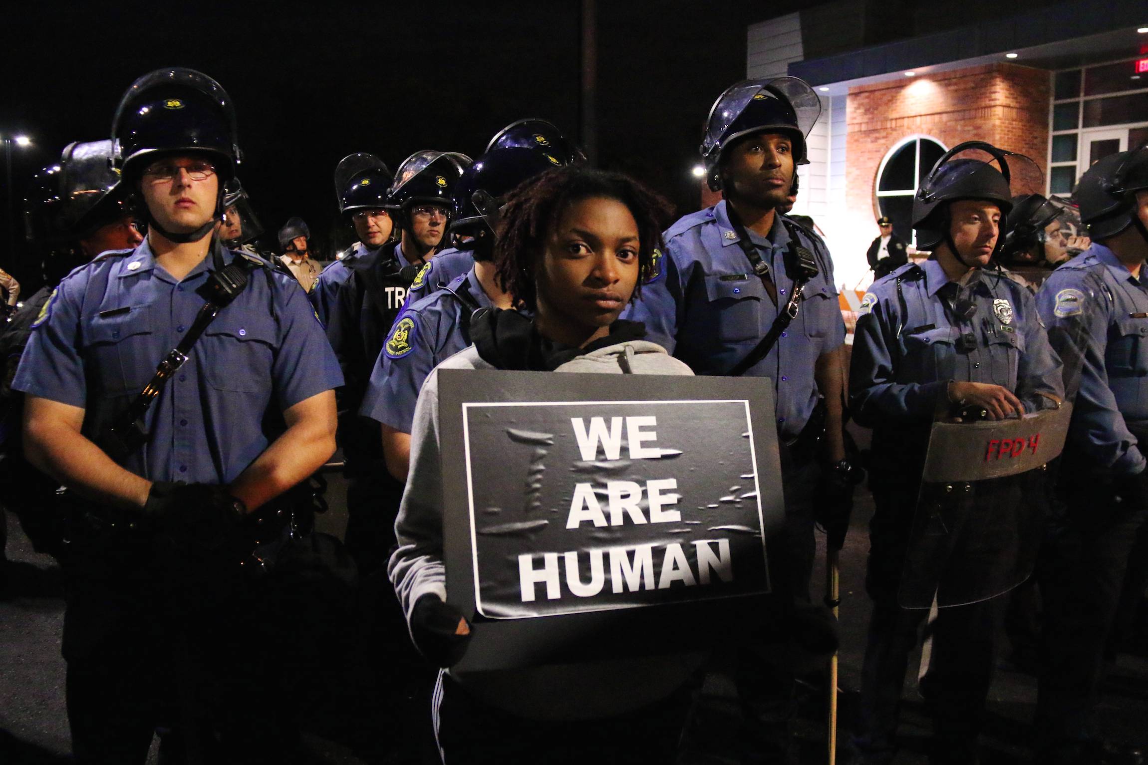 A man holds a sign reading "we are human" during a standoff between police and protesters at the Ferguson Police Departement, in Ferguson, Missouri, Oct. 11, 2014.