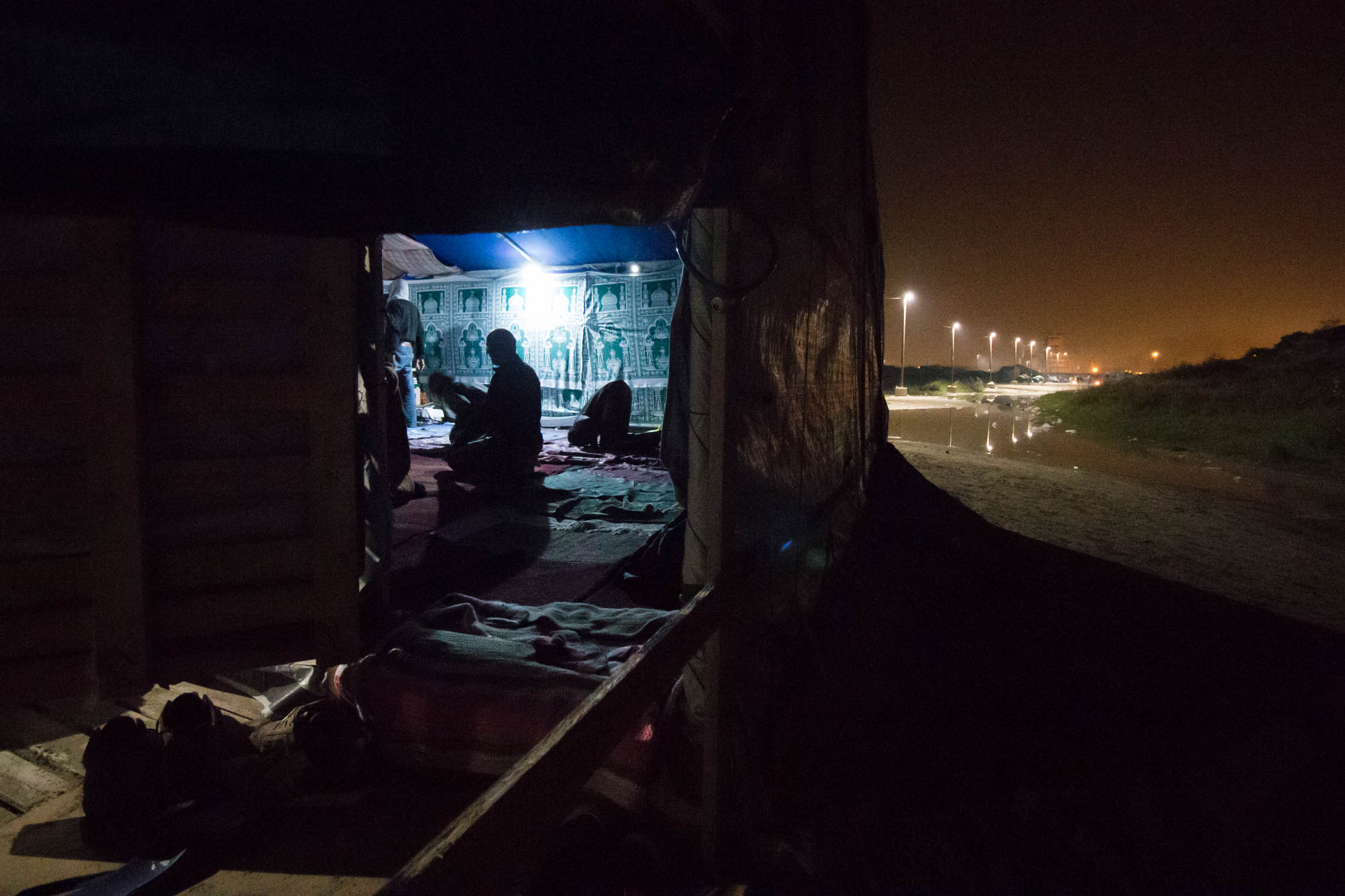 Men pray after sunset in the main mosque at the "New Jungle" refugee camp in Calais, France, Sunday, October 5, 2015.